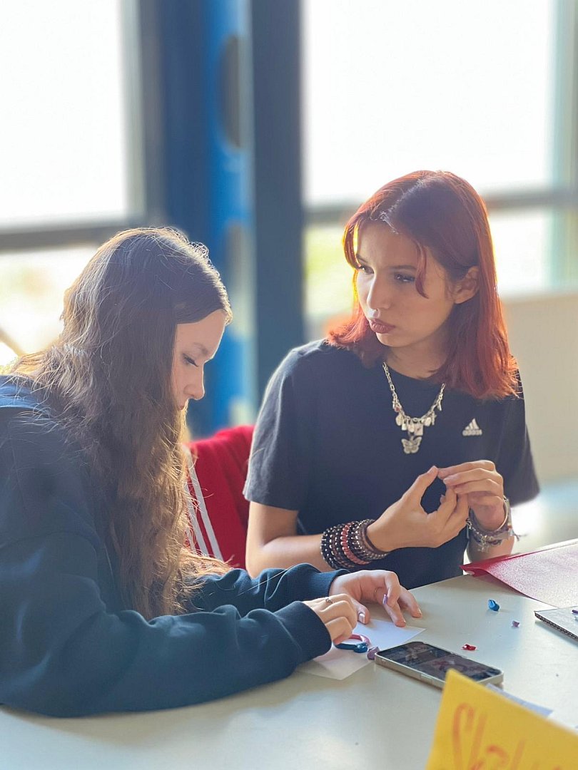zwei Schülerinnen basteln am Tisch und unterhalten sich in der Jugenderberge in Klingenthal