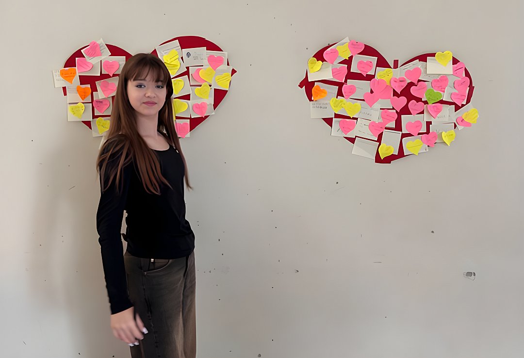 eine Schülerin steht vor zwei an einer Wand befestigten Papierherzen mit Post-Its in der Jugendherberge in Klingenthal