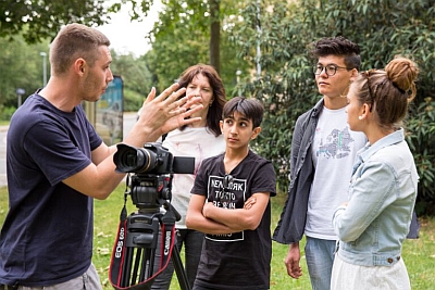 Jugendliche lernen den Umgang mit einer Filmkamera im Park