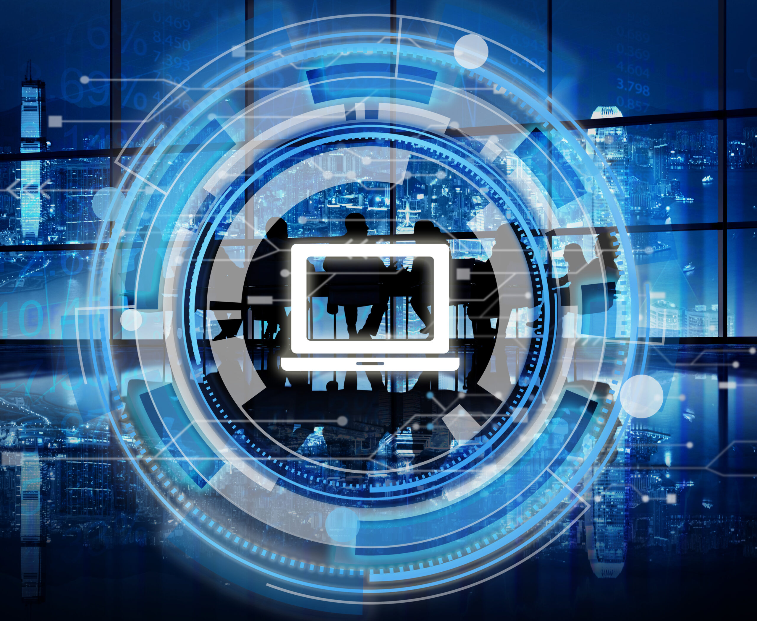 За столом сидят люди, вокруг них размещена цифровая техника, создающая атмосферу современной работы и технологий.