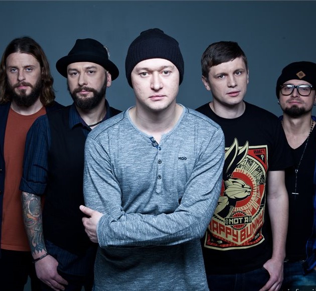 Групповой портрет пяти мужчин, участников группы «Бумбокс», на сером фоне. В центре — солист Андрей Хлывнюк в сером лонгсливе и черной шапке, со сложенными на груди руками. Слева от него стоят двое мужчин: один с татуировками на руках, другой в черной шляпе и жилетке. Справа — двое мужчин в черных футболках, один из которых в очках и шапке. У всех участников спокойные и серьезные выражения лиц. Групповой портрет пяти мужчин, участников группы «Бумбокс», на сером фоне. В центре — солист Андрей Хлывнюк в сером лонгсливе и черной шапке, со сложенными на груди руками. Слева от него стоят двое мужчин: один с татуировками на руках, другой в черной шляпе и жилетке. Справа — двое мужчин в черных футболках, один из которых в очках и шапке. У всех участников спокойные и серьезные выражения лиц.