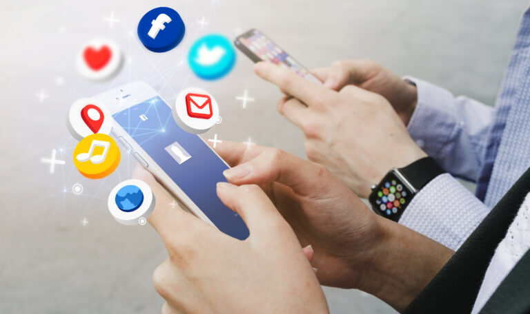 На изображении — мужчина и женщина, стоящие рядом, оба держат в руках мобильные телефоны.