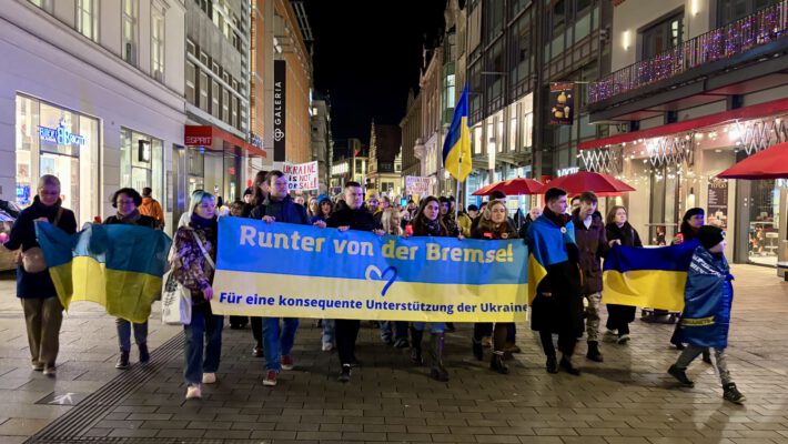 Учасники мітингу на підтримку України в Лейпцигу з великим банером Runter von der Bremse у центрі міста
