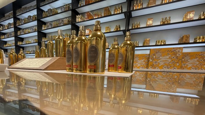 Полки с аккуратно расставленными флаконами духов разных форм и размеров.