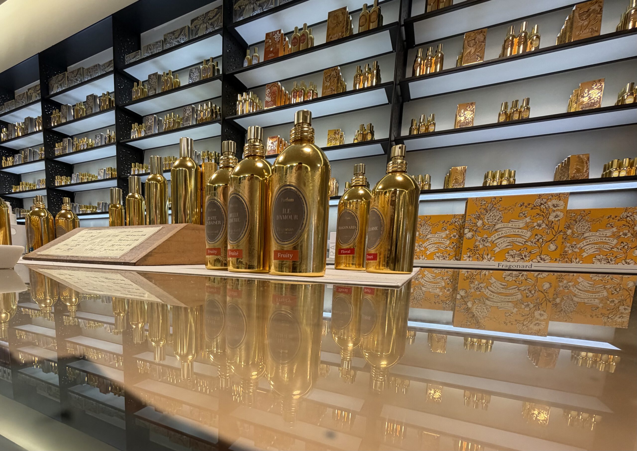 Полки с аккуратно расставленными флаконами духов разных форм и размеров.