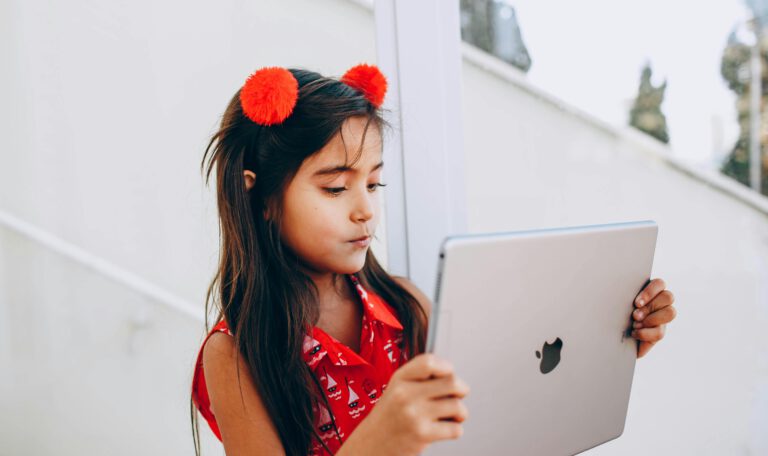 Девочка держит в руках планшет Apple iPad, для которого, согласно директиве ЕС, с апреля 2026 года в Европе станет обязательным единый стандарт зарядки USB-C