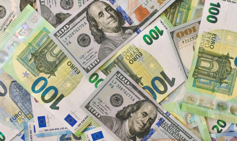 На изображении представлен хаотичный коллаж из бумажных денежных купюр, расположенных под разными углами и перекрывающих друг друга.