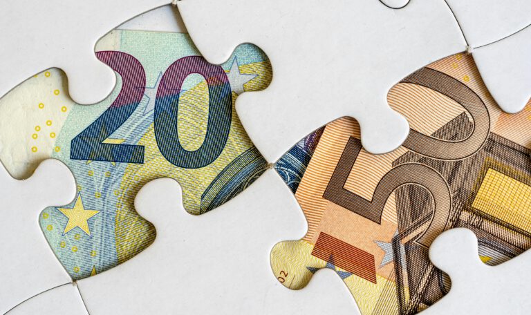 Купюры евро под фрагментами пазла как символ нестабильности потребительских настроений и поиска экономических решений в условиях кризиса