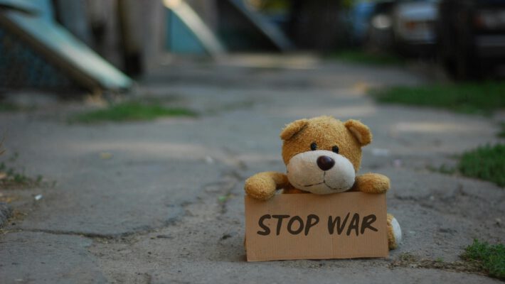 Плюшевый мишка с табличкой "Stop War", иллюстрирующий план массовой эвакуации населения и защиту уязвимых групп в условиях военного кризиса