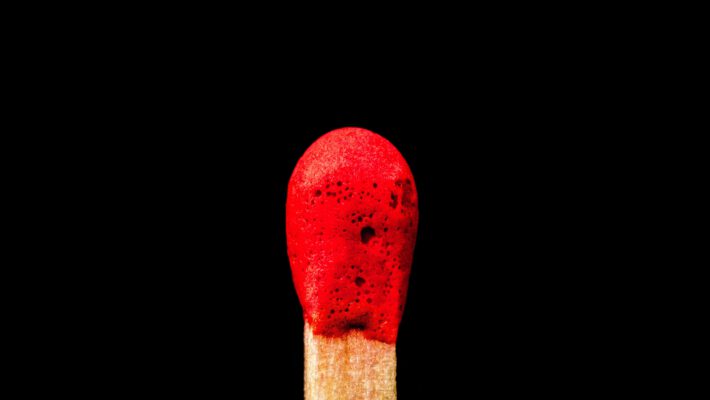 Макросъемка красной спички на черном фоне как символ начала войны с Ираном и эскалации на Ближнем Востоке