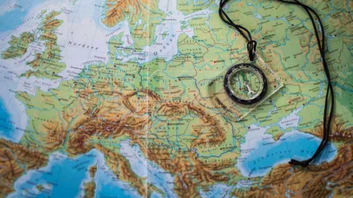 Компас, лежащий на карте Европы, отражающий смену вектора в общественном мнении: европейцы считают угрозой США