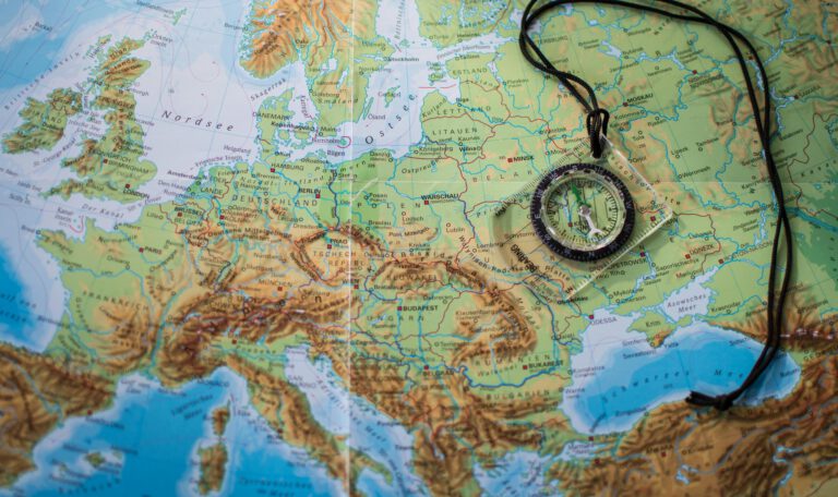 Компас, лежащий на карте Европы, отражающий смену вектора в общественном мнении: европейцы считают угрозой США