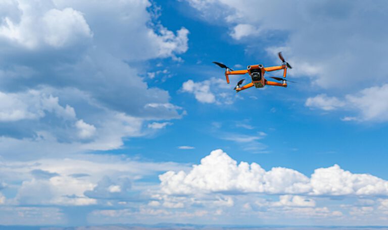 Оранжевый квадрокоптер в небе, символизирующий производство современных БПЛА для европейской безопасности и обороны