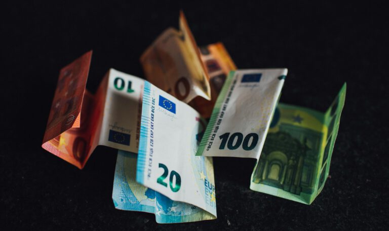 Разбросанные купюры евро номиналом 10, 20 и 100 на темном фоне, символизирующие инфляцию и текущее состояние экономики Германии в 2026 году