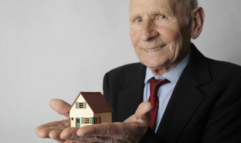 Пожилой мужчина держит миниатюрный дом, символизирующий расходы на проживание и реформу системы ухода в Германии
