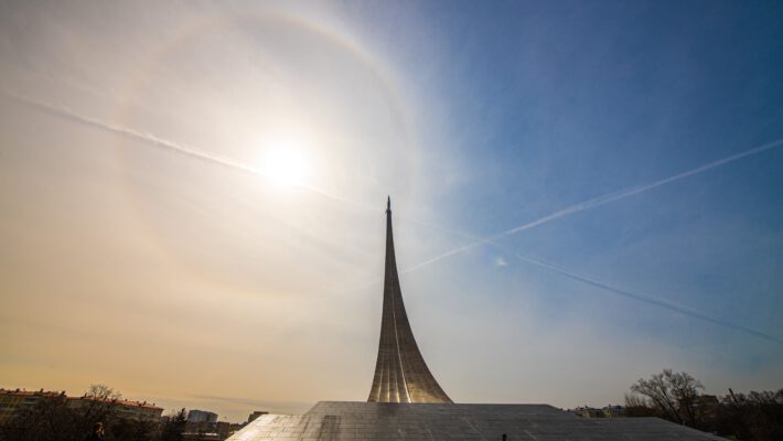 Німеччина вп'ятеро збільшує підтримку меморіалу «Яд Вашем». Величний титановий монумент у формі шлейфу від ракети, що стрімко злітає вгору, розташований на широкому кам'яному постаменті. На світлому небі яскраво світить сонце, утворюючи навколо себе кругове гало. Небо перетинають тонкі білі інверсійні сліди від літаків. На передньому плані видно силуети кількох людей, які гуляють площею біля пам'ятника.