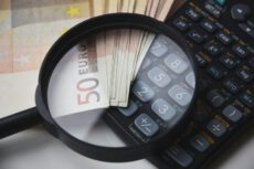 Крупный план пачки банкнот номиналом 50 евро и инженерного калькулятора, рассматриваемых через черную лупу. Экспорт Германии.
