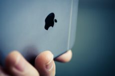 Верхня частина сірої задньої панелі телефону Apple, що тримається горизонтально, знаходиться у фокусі. Зліва внизу її закриває верхня частина безіменного та мізинця лівої руки з нігтями, які тримають пристрій. В центрі задньої панелі розташоване надкушене яблуко. Зверху над яблуком на задній панелі, і ще вище, де вона стикається з торцем, проходять дві горизонтальні смуги. На тлі нерівномірно затемнене розмите узлісся в сірих відтінках. iCloud+ безкоштовно Apple TV Arcade Україна. Верхня частина сірої задньої панелі телефону Apple, що тримається горизонтально, знаходиться у фокусі. Зліва внизу її закриває верхня частина безіменного та мізинця лівої руки з нігтями, які тримають пристрій. В центрі задньої панелі розташоване надкушене яблуко. Зверху над яблуком на задній панелі, і ще вище, де вона стикається з торцем, проходять дві горизонтальні смуги. На тлі нерівномірно затемнене розмите узлісся в сірих відтінках. iCloud+ безкоштовно Apple TV Arcade Україна.